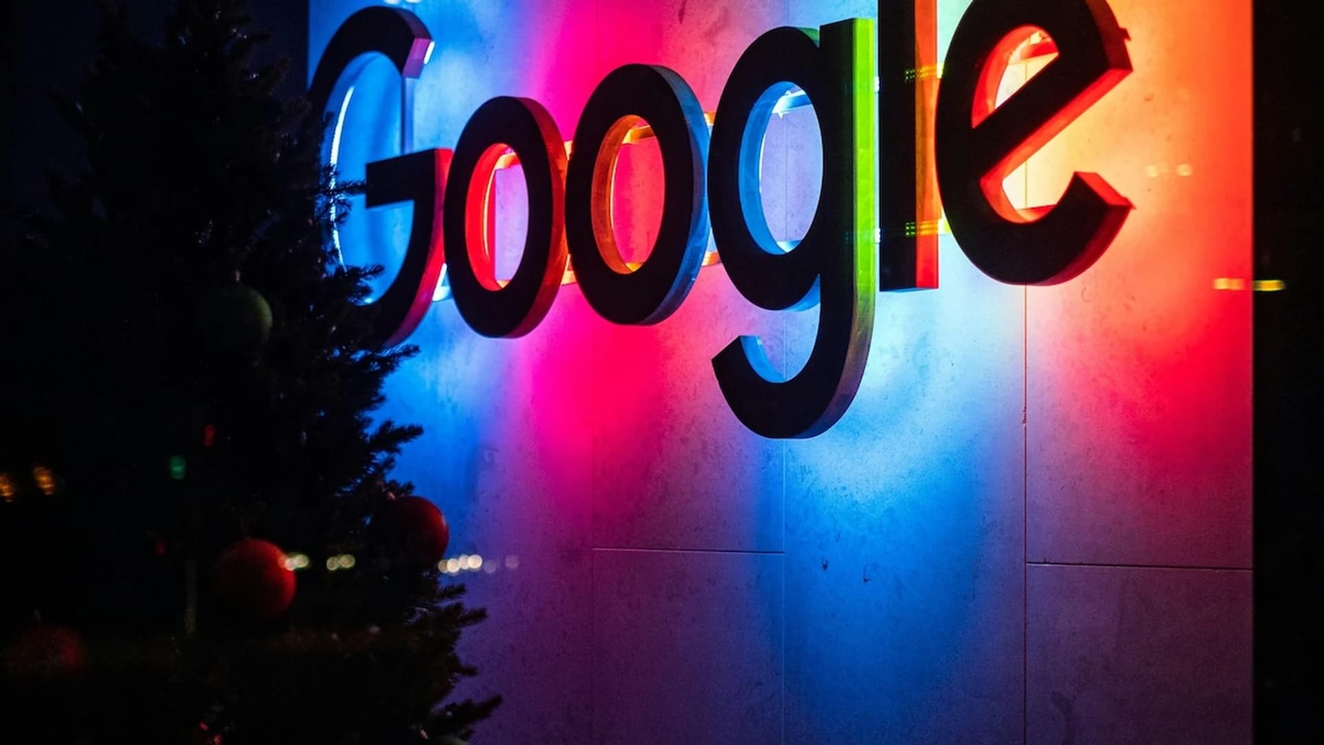 Letrero gigante iluminado de Google sobre una pared con luces rojas, azules y rosas en una recepción corporativa — playbook de SEO para el 2026