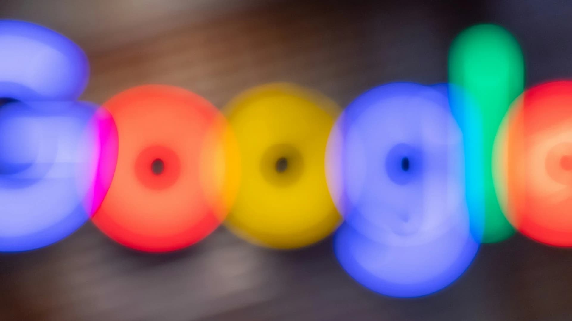 Logo de Google con efecto de movimiento desenfocado en azul, rojo, amarillo y verde sobre superficie de madera — guía de SEO 2026 para el SERP y los motores de IA
